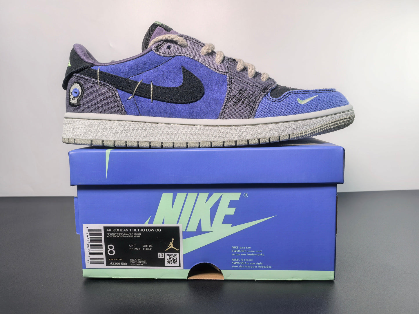 Air Jordan 1 Retro Low OG sneaker in purple and grey on a blue Nike box, luxury urban wear